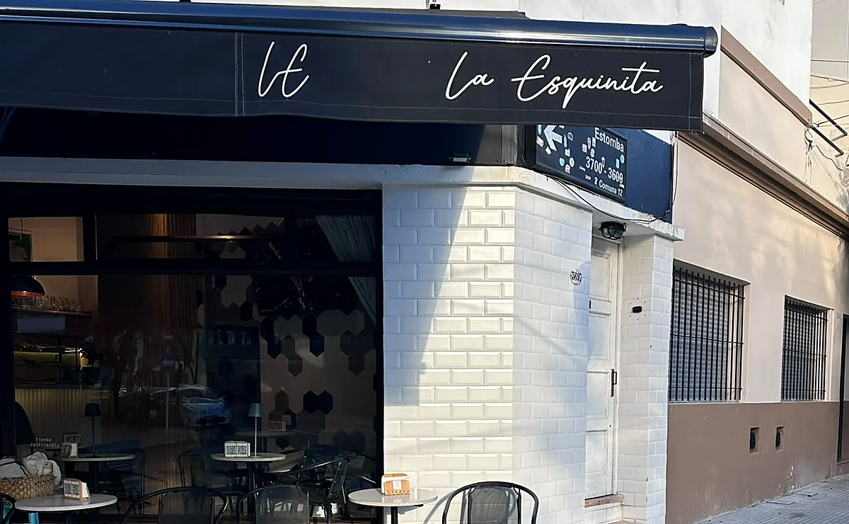 El frente de La Esquinita con el toldo, el isologo LE y las mesas en la vereda