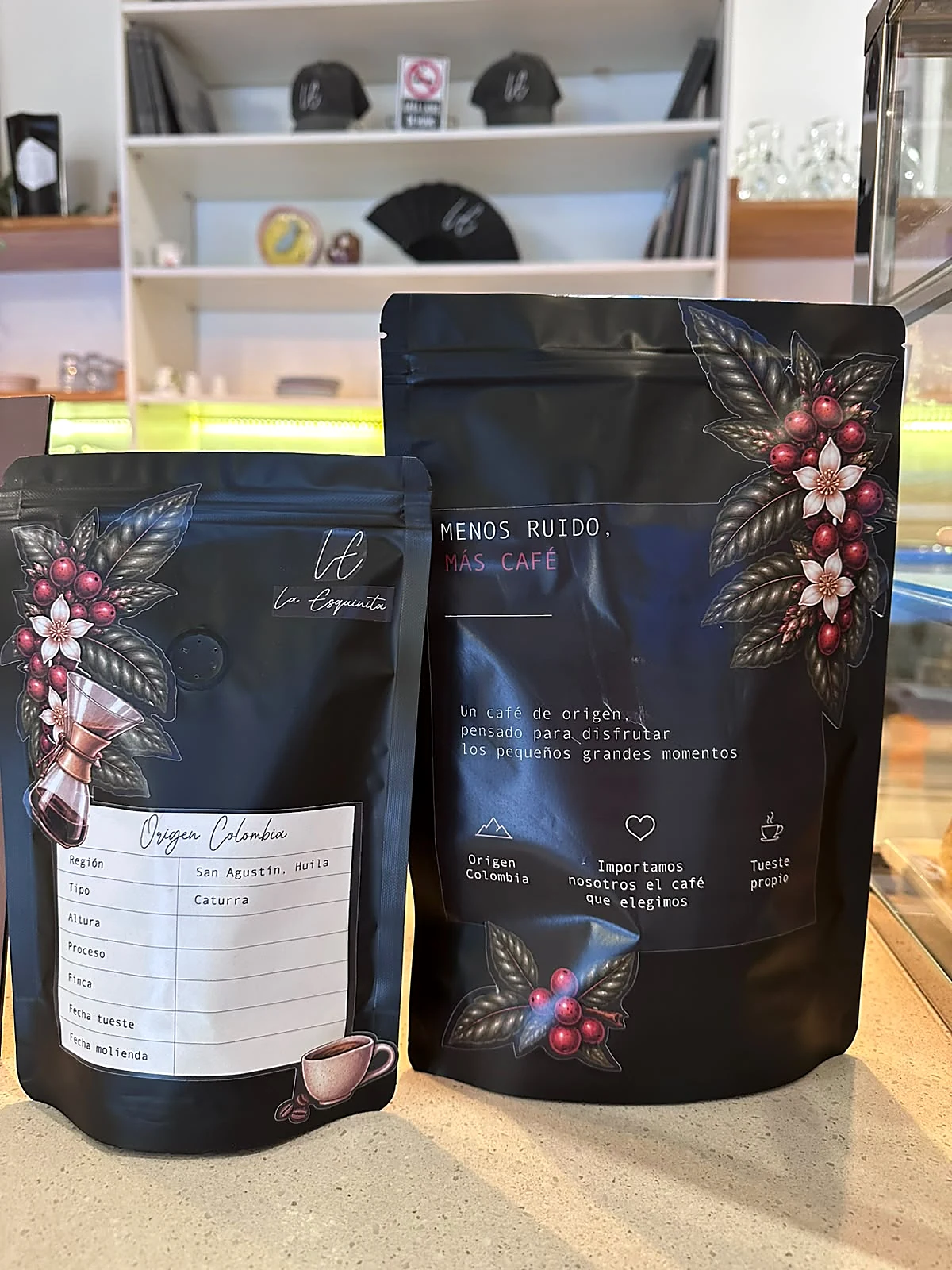 Las bolsas de café de La Esquinita de 250 y 500 gramos: negras, con cerezas de café ilustradas y la frase Menos ruido, más café